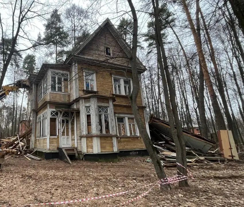 Трёхэтажный деревянный дом с резными верандами в лесу перед разборкой